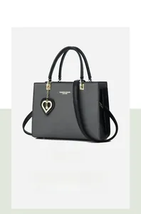 Detail view of grey woven texture tote with black handles and a pearl heart pendant