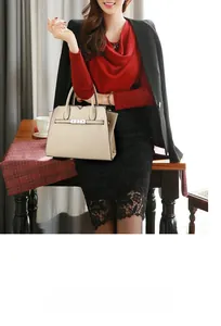 Detail of beige lychee textured leather handbag with metallic clasp and dual handles