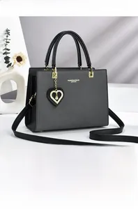 Detail of elegant black tote bag featuring gold lettering and heart pearl pendant charm