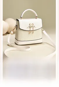 Détail du sac crème avec fermoir cygne doré, texture plissée et petites perles