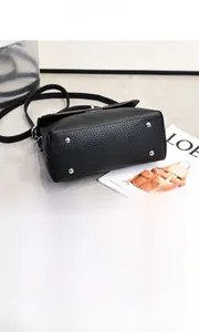 Detail der schwarzen Lederhandtasche mit Metallfüßen und einem Schultergurt