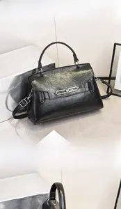 Detail view of black pleated faux leather handbag with silver twist lock and round handle
