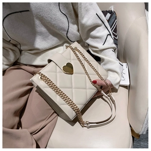 Detail of beige quilted crossbody bag with golden heart-shaped lock and chain strap