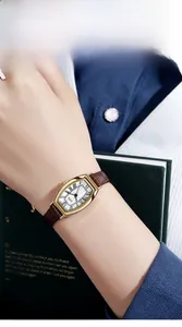 Close-up of a vintage tonneau quartz watch with Roman numerals on a leather strap