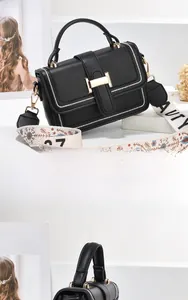 Detail der schwarzen Ledertasche mit goldenem H-Verschluss und Vintage-Blumenschultergurt