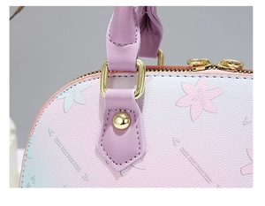 Macro detail of lychee texture gradient shell bag with gold hardware and floral pattern