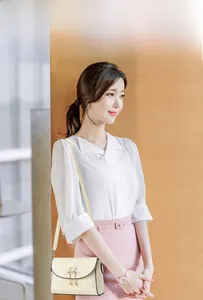 Detail of cream flap shoulder bag featuring quilted texture and golden swan lock on model