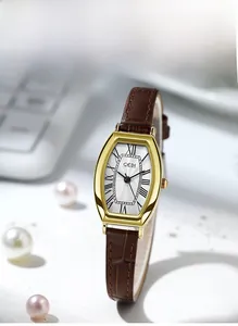 Close-up of a vintage tonneau quartz watch with roman numerals and brown leather strap