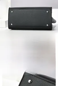 Detailed view of silver protective metal studs on the black lychee pattern bag base