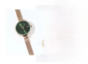 Détail de la montre à maille rose doré avec cadran vert soleil et guichet de date