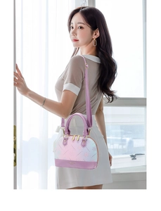 Detail of pink floral gradient shell bag featuring gold hardware and purple leather handle