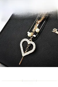 Detail of black lychee leather texture with gold heart pendant and white pearls