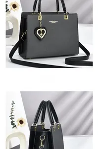 Detail of black textured handbag with heart pearl charm and golden hardware