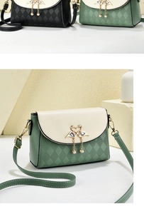 Detail of elegant swan charm with pearls and quilted texture on small crossbody bag