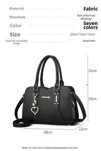 Detailed view of a black top-handle bag with gold hardware and a heart-shaped pendant