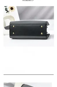 Detail view of the black leather bag bottom with four protective gold metal feet studs