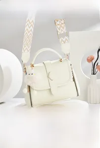 Détail du sac bandoulière crème avec sangle jacquard et breloque en peluche mignonne