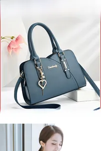Detail of dark blue pebbled leather handbag with pearl heart charm and metal logo plate