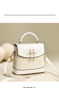 Détail du sac à main crème avec texture plissée et fermoir cygne doré orné de perles