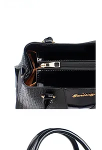 Detail der schwarzen Lackhandtasche mit Krokodilprägung, Gold-Reißverschluss und Logo