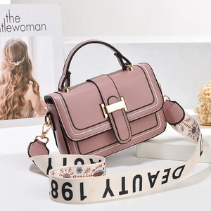 Rosafarbene matte Ledertasche mit floralem breitem Schultergurt auf weißem Podest