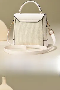 Vue détaillée du dos d'un sac bandoulière beige texturé avec des bords noirs contrastés