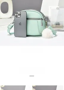 Mini mint green crossbody bag with lychee texture and plush ball compared to an iPhone