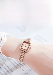Gros plan sur la montre carrée or rose avec marqueurs en cristal sur manche en dentelle