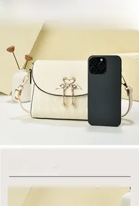 Close-up of cream quilted crossbody bag with gold swan buckle and chain strap