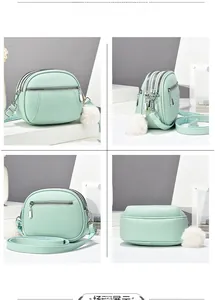 Mint green textured leather crossbody bag with three zip layers and plush pompom charm