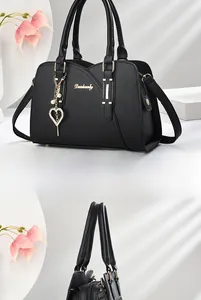 Detail of black lychee texture handbag with gold hardware and pearl heart charm