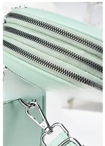 Detail view of smooth silver zippers and mint green leather texture on a crossbody bag