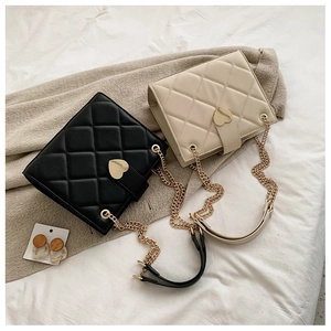 Detail of elegant quilted tote bags with heart-shaped gold buckles in black and beige