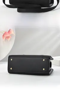 Close-up of black lychee leather bag bottom with four golden metal protective feet