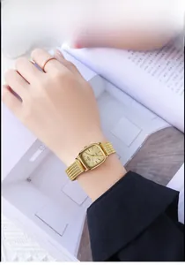 Detail of vintage gold square watch with metallic mesh strap worn on a wrist