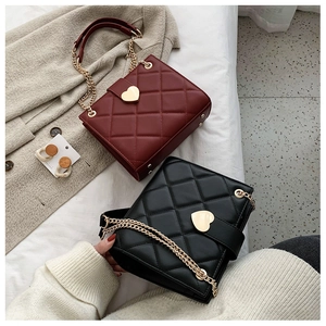 Detail of red and black quilted bags with heart buckles and gold chain straps