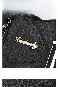 Macro view of black lychee grain leather handbag featuring gold Danbaoly logo and chain