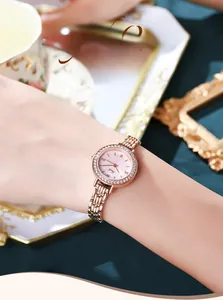 Close-up of rose gold watch with rhinestone bezel worn on wrist in a luxury setting