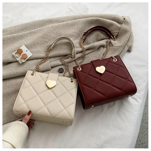 Quilted tote bags in beige and red featuring a gold heart-shaped metal buckle detail