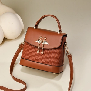 Sac à main en cuir marron avec boucle flamant rose et pompons en perles, vue à 45 degrés