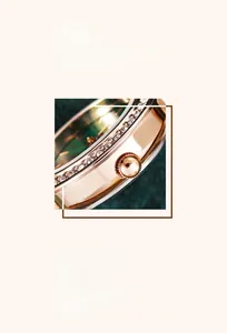 Macro shot of rose gold watch case with crystal-set bezel and dark green dial
