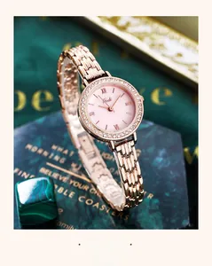 Detail of rose gold quartz watch with rhinestone bezel on green marble background