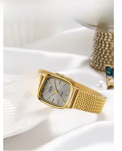 Close-up of golden square quartz watch with a grey textured dial on white silk