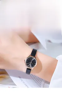 Detail of rose gold watch with black dial and leather strap on model's wrist