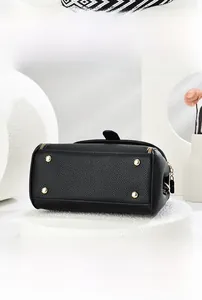 Détail du dessous du sac en cuir noir avec quatre pieds de protection en métal doré