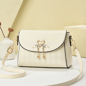 Beige crossbody bag with gold swan buckle and pearl detail in a lifestyle setting