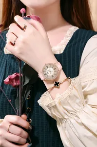 Détail d'une montre en cuir rose avec lunette en strass et bracelet trèfle au poignet