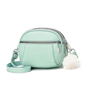 Mint green triple zipper mini crossbody bag in lychee faux leather with plush ball
