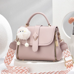 Handtasche aus rosafarbenem Leder mit Lychee-Muster, breitem Gurt und weißem Pompon