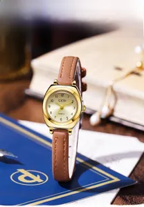 Détail du cadran tonneau champagne vintage et du bracelet en cuir marron sur bois